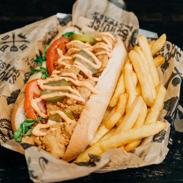 Salty Joe's BBQ fried shrimp po'boy with pickles, tomatoes, lettuce, and fries in a basket.