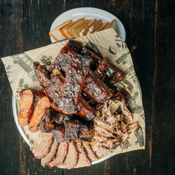 A platter of Salty Joe's BBQ ribs, brisket, pulled pork, and sausage with toast.